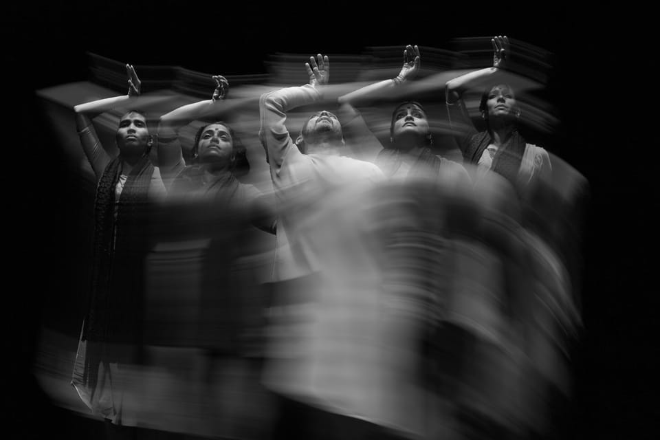 Black and white double exposure photograph of dancers, combining sharp figures with motion blur, creating an effect where stillness and movement exist simultaneously